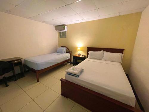 瓜亚基尔加尔萨别墅旅馆的一间卧室配有两张床和一张带台灯的桌子