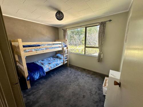 罗托鲁瓦Streamside Family Friendly Oasis with Spa的一间卧室设有两张双层床和一扇窗户。