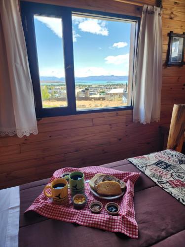 埃尔卡拉法特艾乐琛山林小屋的一张桌子,床上放着一个食物盘,还有窗户