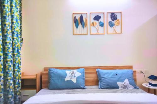 达波林Quiet & Cozy Resort Style Fully Furnished 1-BHK Apartment的一间卧室配有一张带蓝色枕头的床,墙上挂有图片