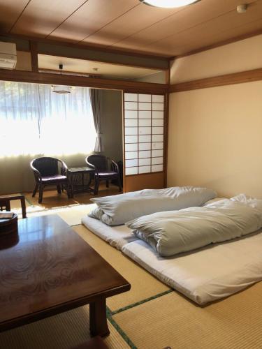 富士河口湖若水荘日式旅馆的一间设有两张床和一张桌子的房间