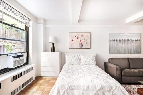 纽约Cozy Studio Apartment的白色卧室配有床和沙发