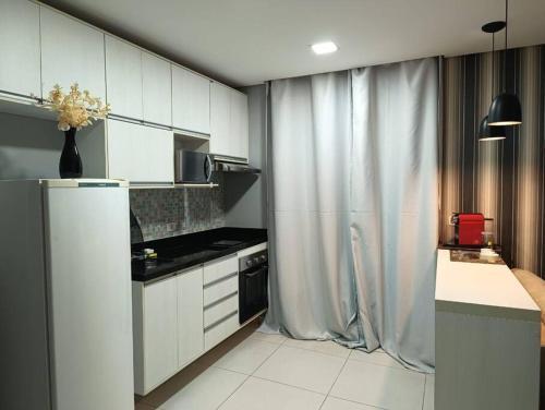 瓜鲁柳斯Loft Completo próx. GRU airport的厨房配有白色橱柜和冰箱。