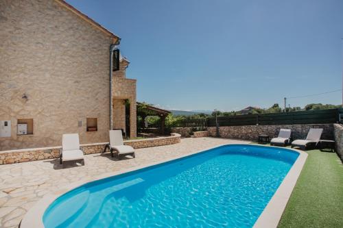罗佐瓦克Kalpic Suites & Villa的一个带椅子的游泳池以及一座房子