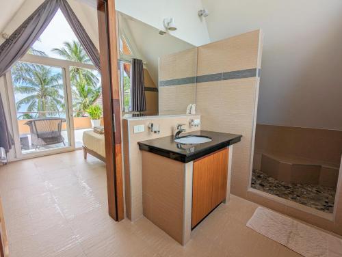象岛Beachfront 5-bedroom Villa的一间带水槽和浴缸的浴室,并设有一个窗口