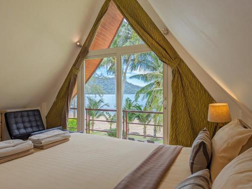 象岛Beachfront 5-bedroom Villa的卧室设有大窗户、一张床和一把椅子