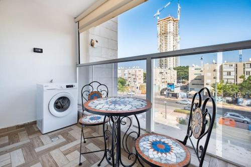 阿什杜德Studio Unit in Ashdod Israel的阳台配有桌椅和洗衣机。
