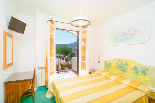 伊斯基亚普林西比温泉酒店的一间带一张床和一张书桌的卧室以及一个阳台