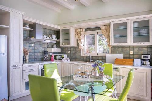 塞沃塔Sivota Villas with Sea Access的厨房配有玻璃桌和绿色椅子