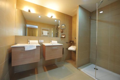 施韦夏特Das Reinisch Hotel & Restaurant的一间带两个盥洗盆和淋浴的浴室