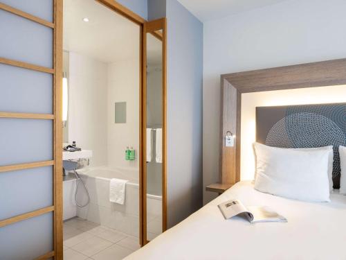 梅赫伦梅赫伦中心诺富特酒店的一间卧室配有一张床,浴室设有浴缸