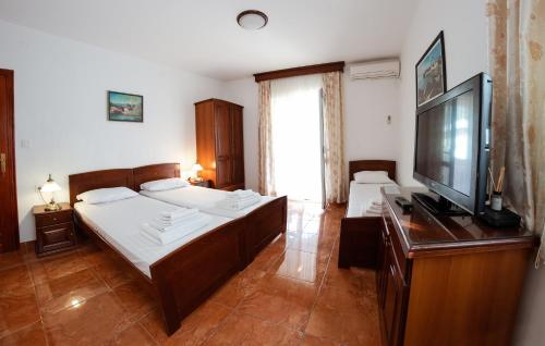 布德瓦Villa MD的一间卧室配有两张床和一台平面电视