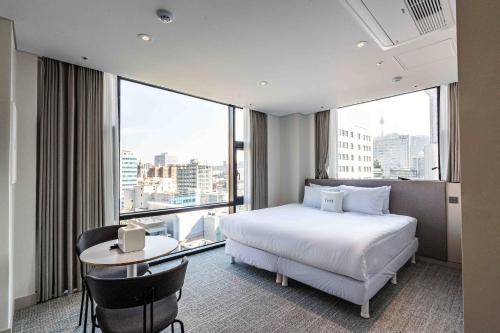 首尔Hotel Vert的一间卧室配有一张床、一张书桌和一个大窗户