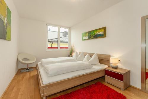 斯拉德明Appartements Tamino by Schladming-Appartements的卧室配有一张白色大床和红色地毯