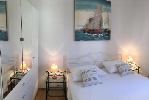 波尔Apartments Eastern Paradise的卧室配有一张白色床,墙上挂着帆船画