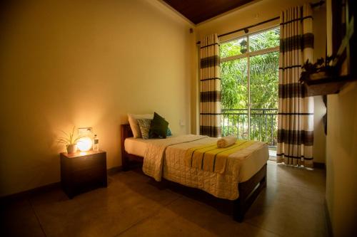 丹不拉Evergreen Hotel Dambulla的一间卧室配有一张带灯和窗户的床