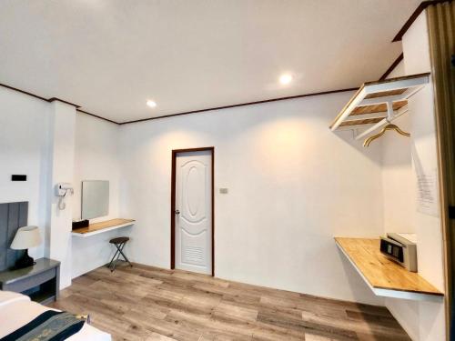 拉迈苏梅岛沙罗查别墅三棵树度假酒店的一间设有一扇门和一张书桌的白色墙壁客房