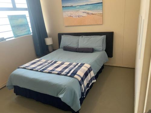 德班The Waves, 302 Quayside Point Waterfront的一间卧室配有一张带蓝白色毯子的床