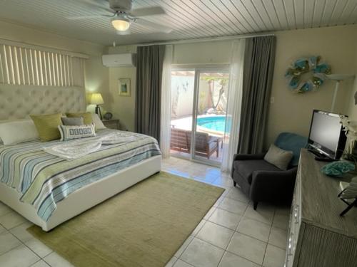 棕榈滩Beachside Villa at Boca Catalina的一间卧室配有一张床、一台电视和一把椅子