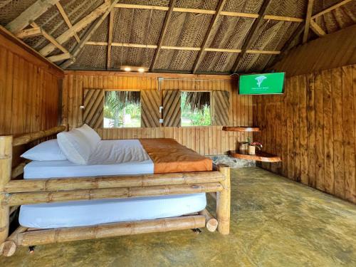 埃尔扎伊诺Tayrona Cachaco River Ecohostal的木制客房内的一间卧室配有两张床