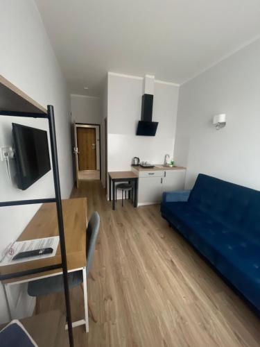 埃尔布隆格Aparthotel Dworzec的客厅配有蓝色的沙发和书桌