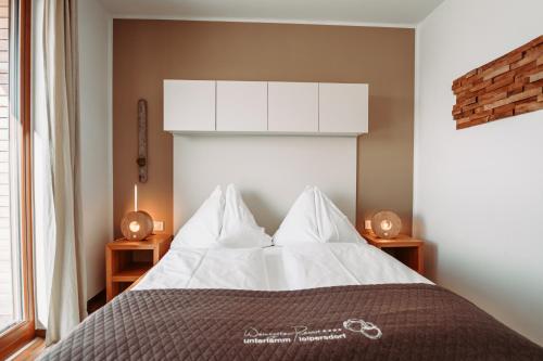UnterlammWeinHAUS 03 im Weingarten-Resort Unterlamm Loipersdorf - ADULTS ONLY的一间卧室配有带白色床单和枕头的床。