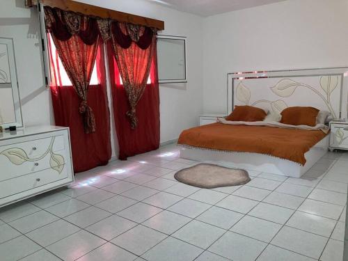 LabattoirL’escale petite terre的一间卧室配有一张带红色窗帘的床和一扇窗户