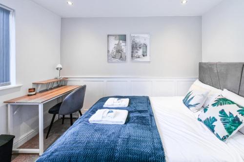 曼彻斯特Great Stunning Two Bedroom Apartment With Balcony的一间卧室配有一张带书桌的床和一张四柱床。