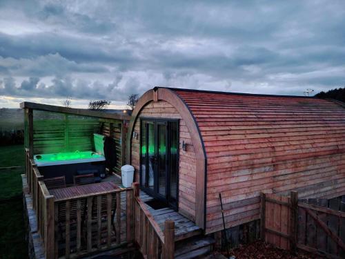 GlenluceBeautiful Glamping Pod with Central Heating, Hot Tub, Garden, Balcony & views - close to Cairnryan - The Herons Nest by GBG的一座大型木制建筑,设有绿灯甲板