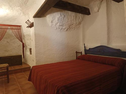 阿尔卡拉德尔胡卡尔Las Cuevas Del Abismo的一间卧室设有红色的床和壁炉