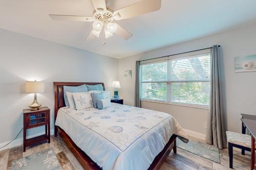 圣奥古斯丁The Harbour Home的一间卧室配有一张带吊扇和窗户的床。
