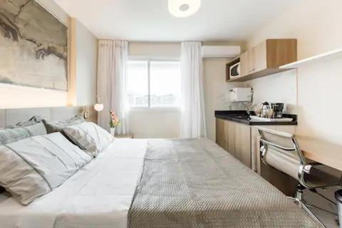 里约热内卢Suite Verano Stay的一间带白色大床的卧室和一间厨房