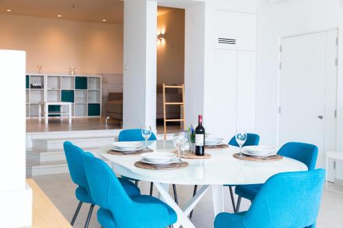 圣朱利安斯Modern apartment in the center of St Julians的白色的用餐室配有白色的桌子和蓝色的椅子