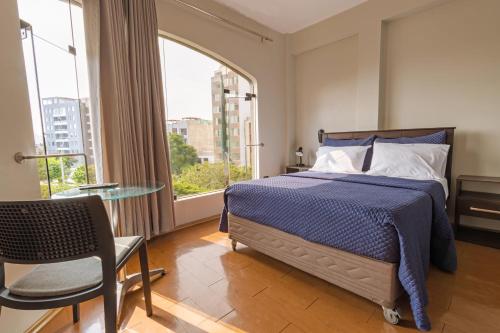 利马San Miguel Awanka Hotel的一间卧室配有一张床、一张桌子和一个窗户。