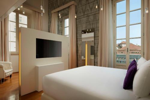 米兰Avani Palazzo Moscova Milan Hotel -Previously NH Palazzo Moscova-的一间卧室配有一张大床和电视