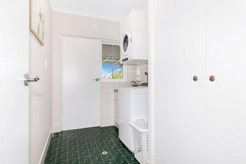 GeographeSandy Feet Retreat的一间带洗衣机和烘干机的浴室,并铺有绿色地板。