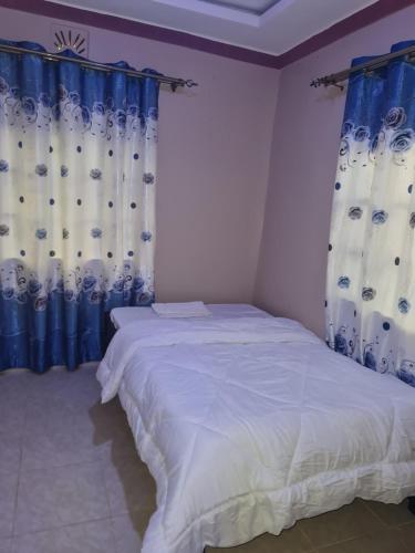 SiayaChrista's haven的一间卧室配有蓝色和白色窗帘的床