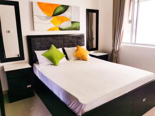 Malabe2 Bedroom Apartment in Colombo, Sri Lanka的一间卧室配有一张带绿色和黄色枕头的床
