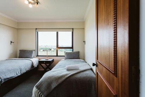 新普利茅斯ABC On Wanaka Bay Support Local的小房间设有两张床和窗户