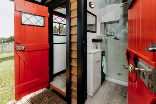 WaitaraOnaero s Quaint Little Cottages的一个小房子里的一个红色门,有水槽