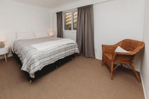 新普利茅斯Wow On Wanaka Bay的卧室配有床、椅子和窗户。