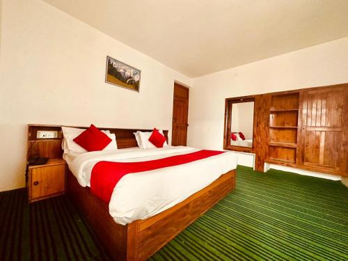 马拉里Hotel Alpine的一间卧室配有一张带红色枕头的大床