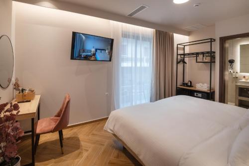 卡拉马塔IRA - ΗΡΑ City Hotel的酒店客房配有一张床、一张书桌和一台电视。