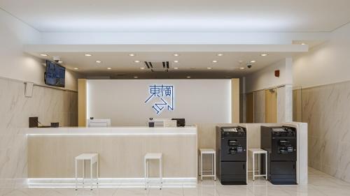 天理市Toyoko Inn Tenri Ekimae的大堂设有柜台和2台自动售货机