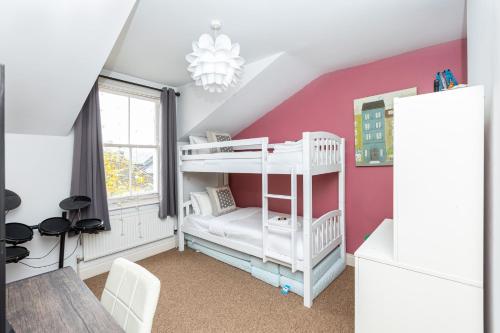 伦敦Beautiful 2BR Flat, Peaceful Dulwich, South London的卧室配有白色双层床和粉红色的墙壁