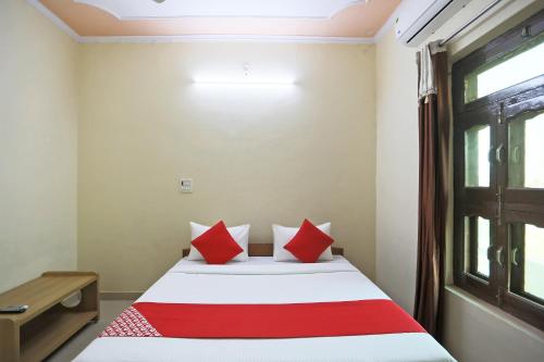 MahendragarhOYO 62761 Hotel Daksh的一间卧室配有一张带红色枕头的床和一扇窗户