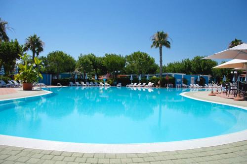 托尔托雷托Villaggio Welcome Riviera d'Abruzzo的一个带椅子和棕榈树的大型游泳池