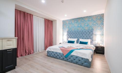 第比利斯Capitol Hotel By umbrella的一间卧室配有蓝色的床和红色窗帘