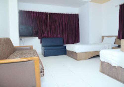JālgaonHotel Kewal INN Jalgaon的酒店客房,设有两张床和一张沙发