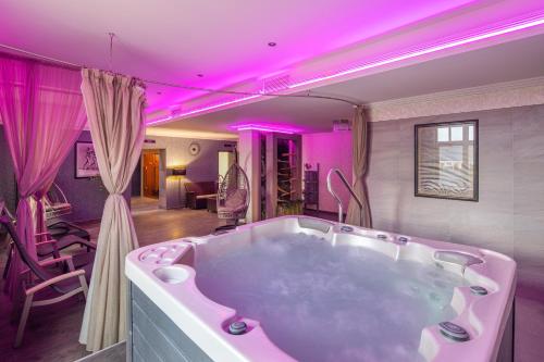 毛科毛科荣耀格兰德酒店的客房内的大浴缸配有粉红色的照明